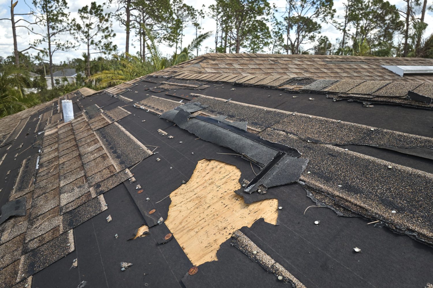 Damaged house roof with missing shingles after hurricane Ian in Florida. Consequences of natural disaster.