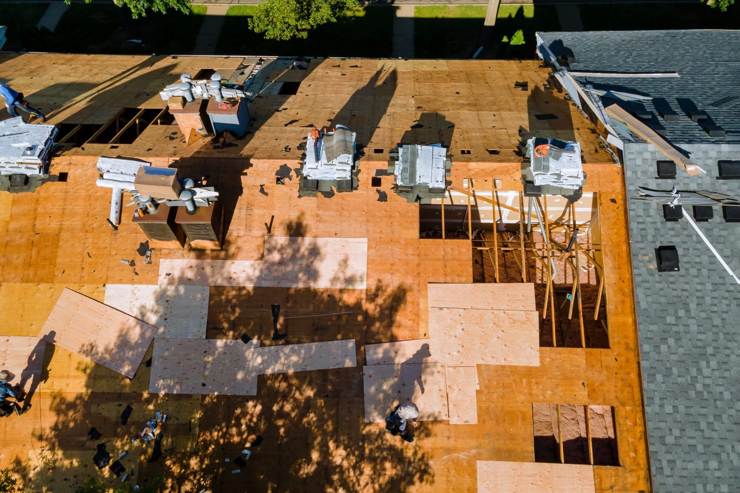 Roof repair, worker with replacing gray asphalt tile shingles on house roofing a construction worker standing on a roof covering